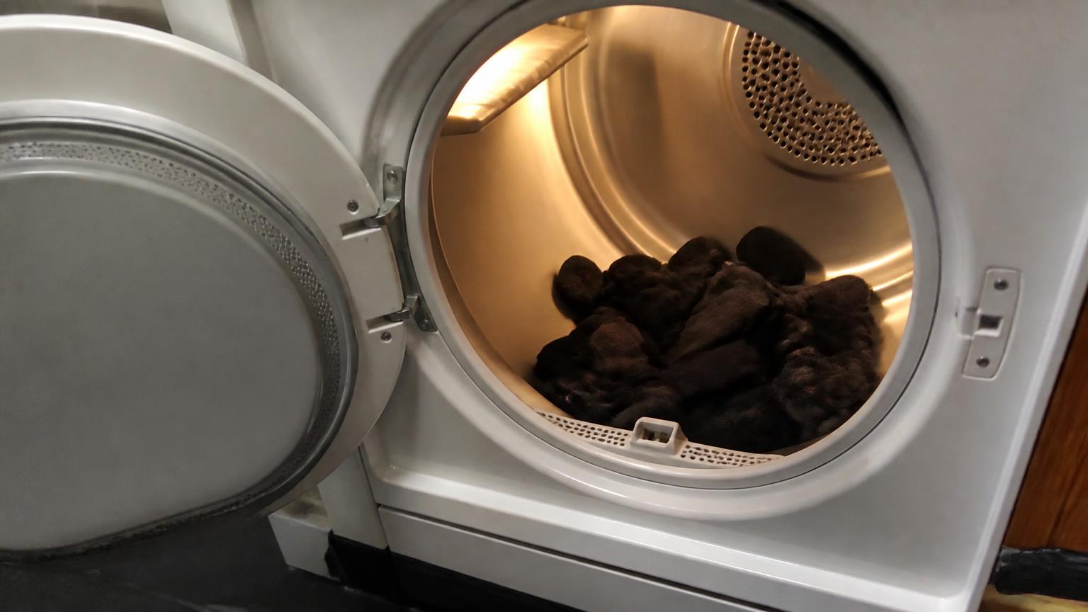 Open tumble dryer drum with dark socks inside